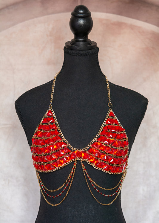 Brassière en cristaux rouges et chaînes d'acier inoxydable et aluminium dorés, pièce statement parfaite pour les festivals, soirées ou looks bohèmes sophistiqués.