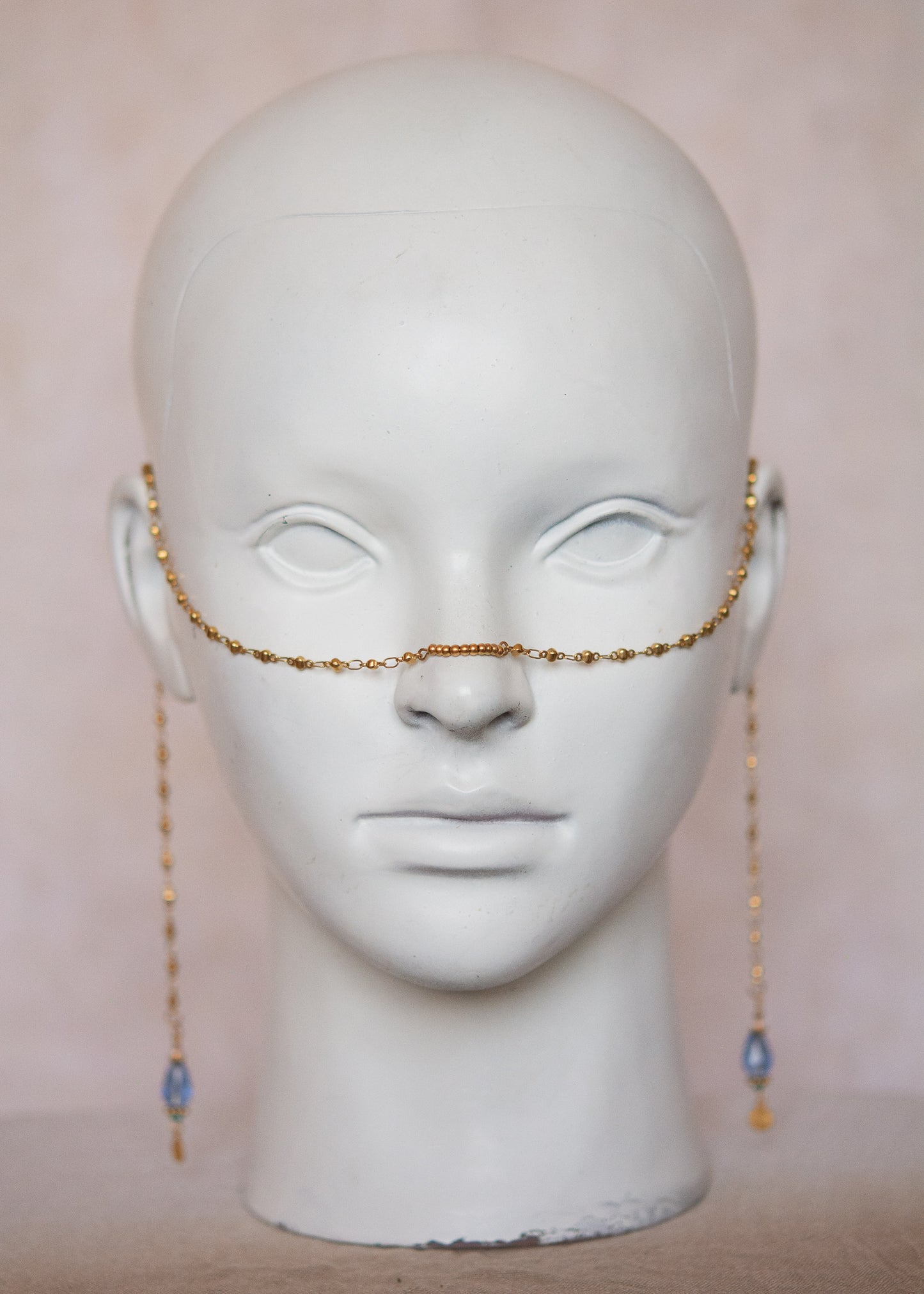 Bijou facial en acier inoxydable doré avec gouttes bleues. Accessoire solaire, pharaonique, festival, costume ou rituel mystique.