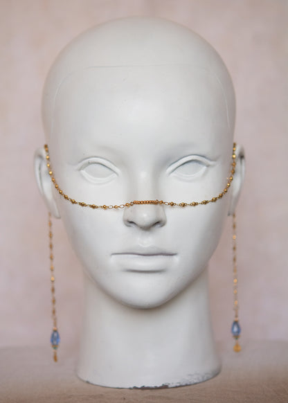 Bijou facial en acier inoxydable doré avec gouttes bleues. Accessoire solaire, pharaonique, festival, costume ou rituel mystique.