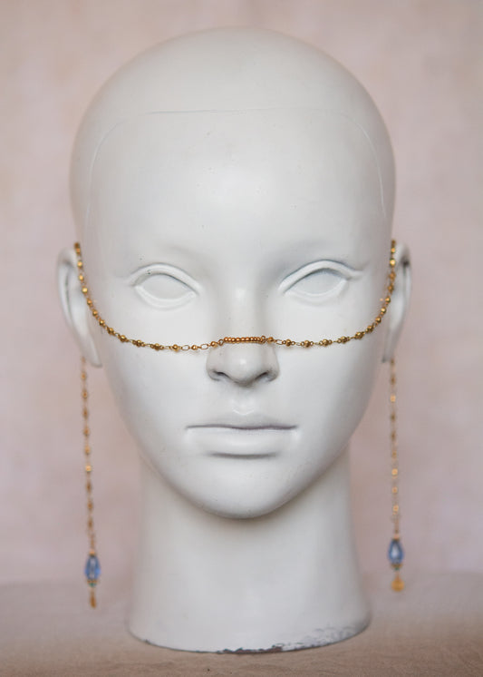 Bijou facial en acier inoxydable doré avec gouttes bleues. Accessoire solaire, pharaonique, festival, costume ou rituel mystique.