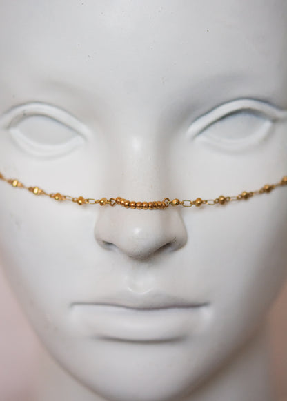 Bijou facial en acier inoxydable doré avec gouttes bleues. Accessoire solaire, pharaonique, festival, costume ou rituel mystique.