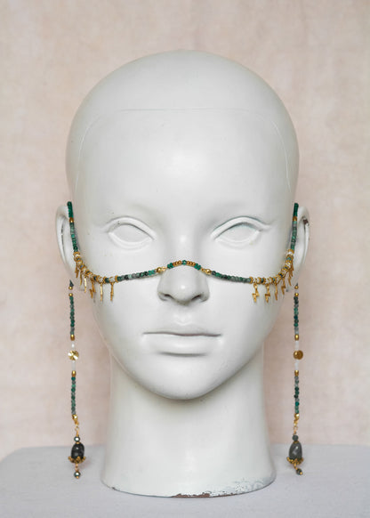 Chaîne de visage avec pierres naturelles de chrysocolla, cristaux verts, détails dorés en acier inoxydable et pierres d’agate indienne | Bijou facial bleu-vert intense | Accessoire de tête artisanal fait main à Montréal | Design structuré et énergique | Pierres fines, éclairs dorés et pont de nez lumineux.