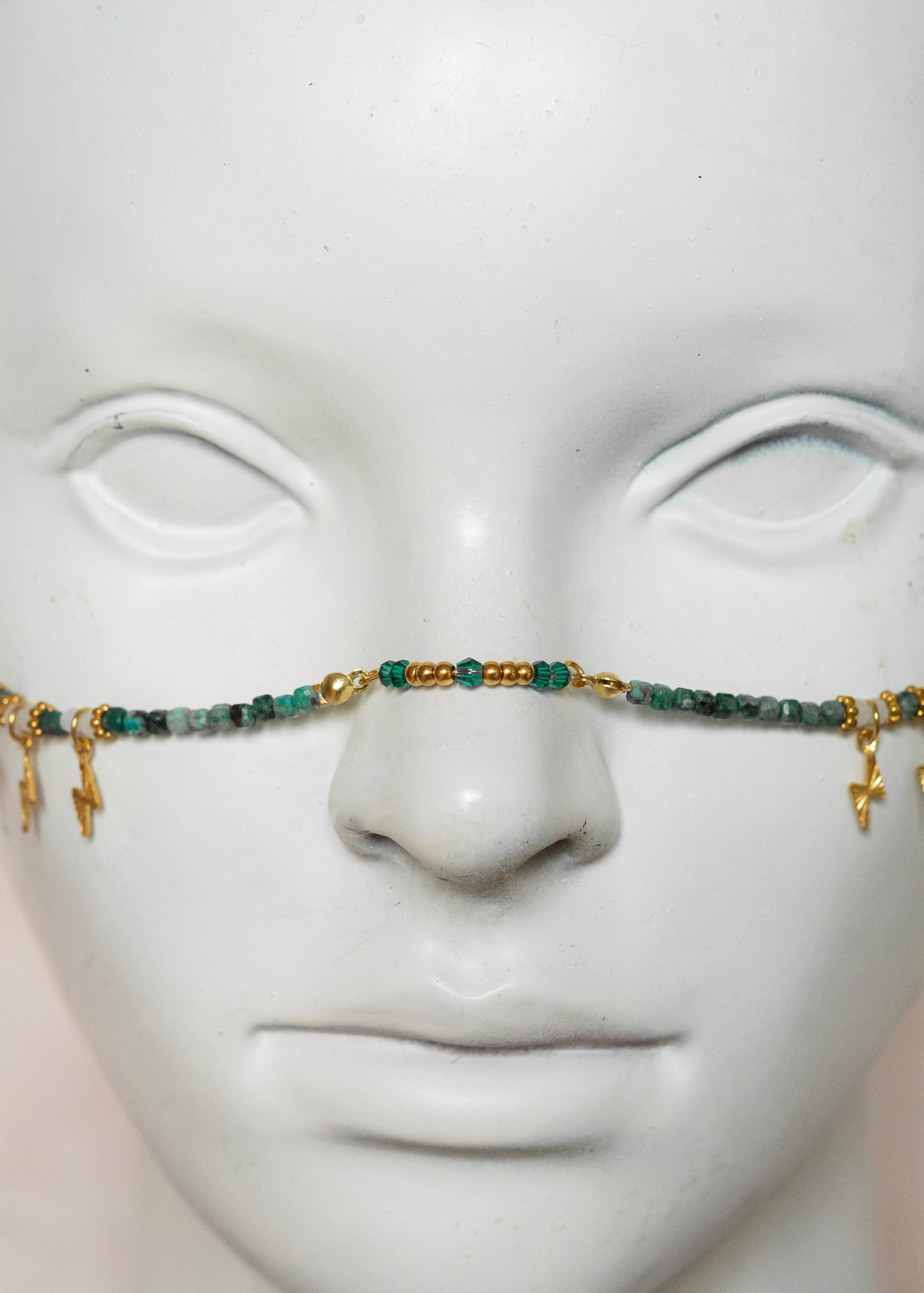 Chaîne de visage avec pierres naturelles de chrysocolla, cristaux verts, détails dorés en acier inoxydable et pierres d’agate indienne | Bijou facial bleu-vert intense | Accessoire de tête artisanal fait main à Montréal | Design structuré et énergique | Pierres fines, éclairs dorés et pont de nez lumineux.