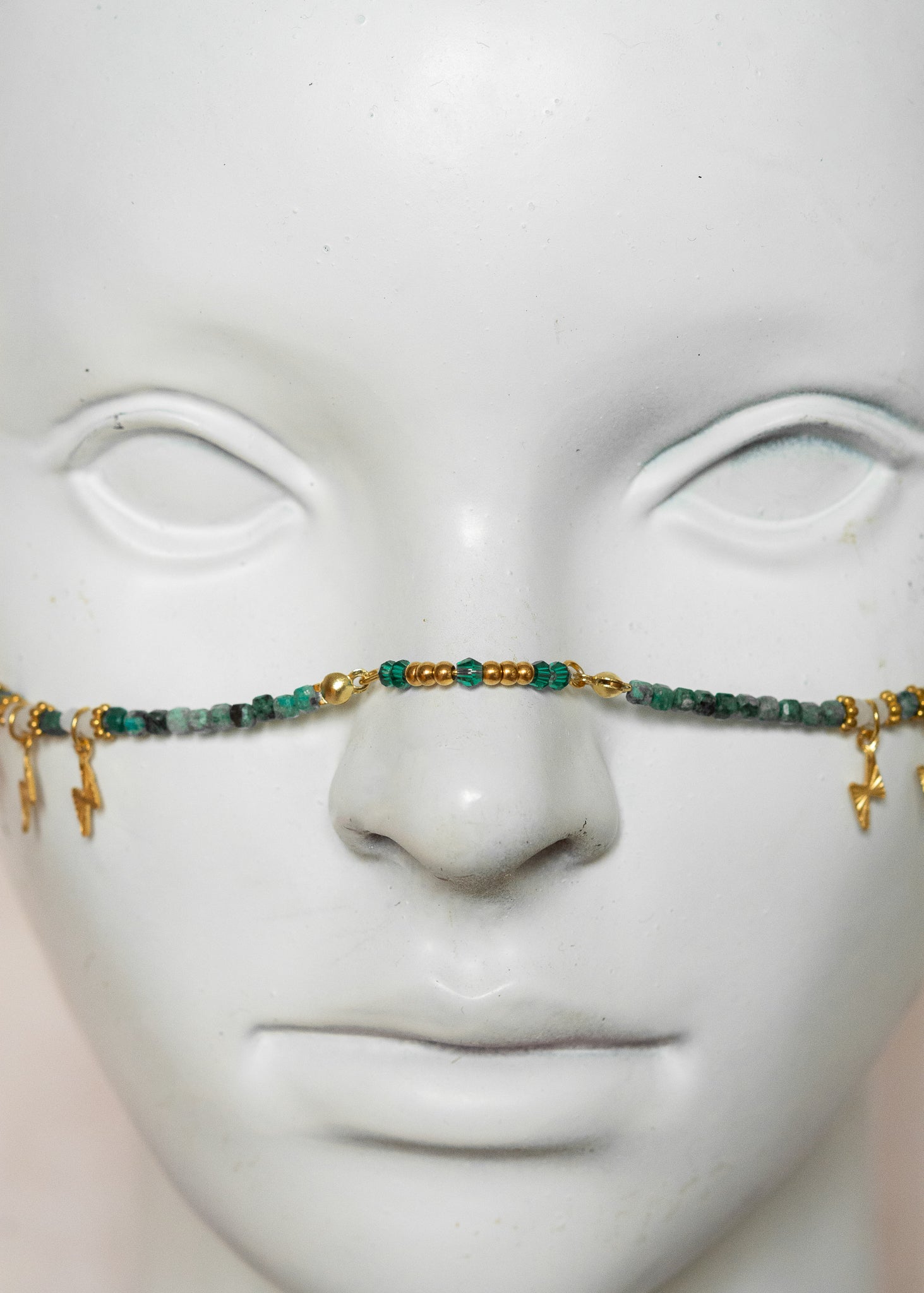 Chaîne de visage avec pierres naturelles de chrysocolla, cristaux verts, détails dorés en acier inoxydable et pierres d’agate indienne | Bijou facial bleu-vert intense | Accessoire de tête artisanal fait main à Montréal | Design structuré et énergique | Pierres fines, éclairs dorés et pont de nez lumineux.