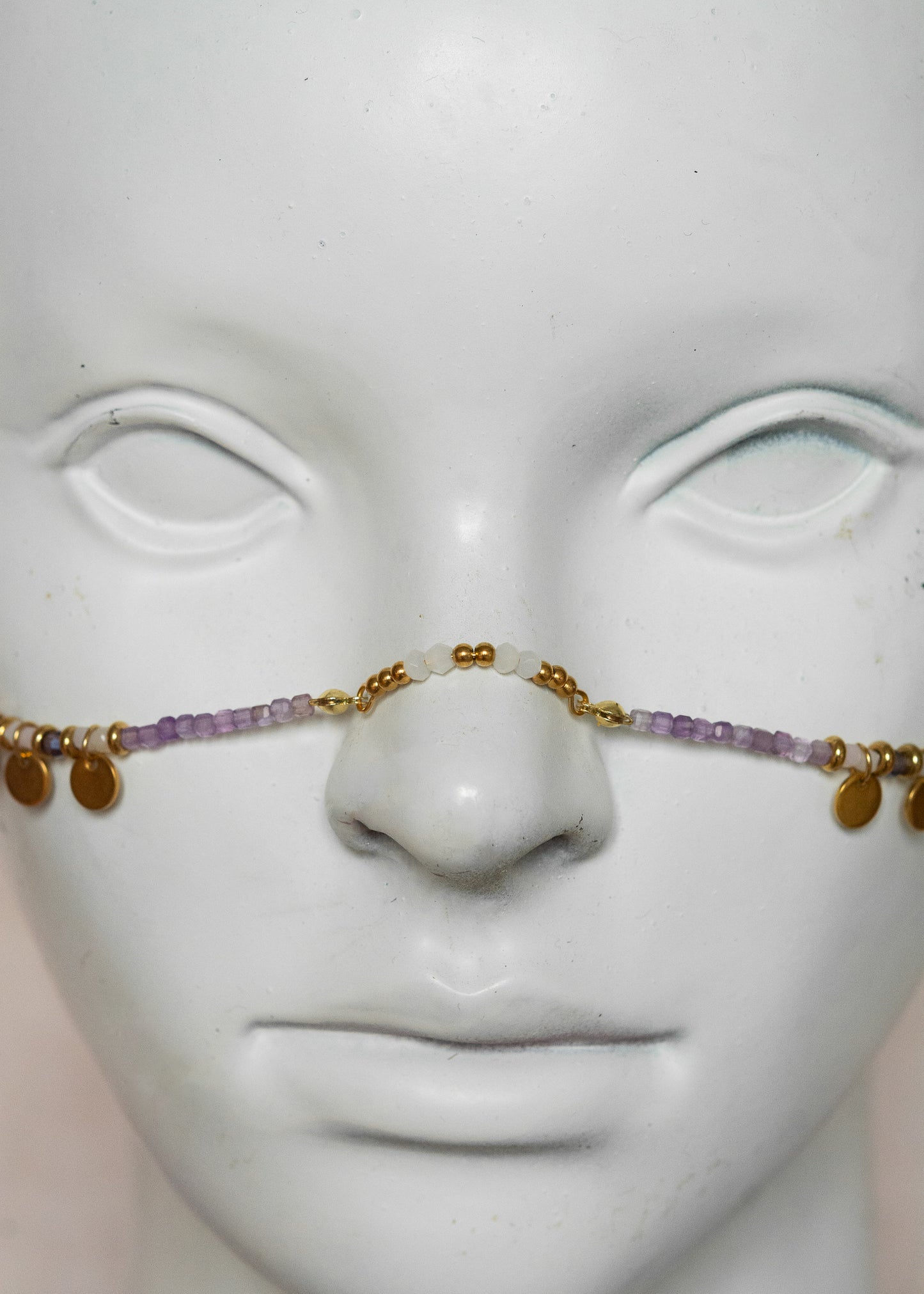 Chaîne de visage avec pierres naturelles d’améthyste et éléments en acier inoxydable doré | Croix stylisées aux extrémités, étoiles dorées et strass translucides sur les joues | Accessoire facial artisanal fait main à Montréal | Bijou de tête pour festival, costume ou tenue artistique | Idéal pour scène, spectacle ou événement spécial.