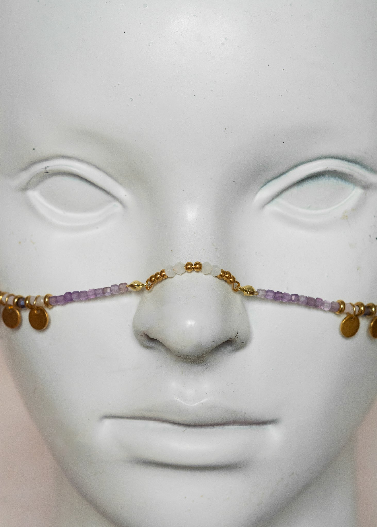 Chaîne de visage avec pierres naturelles d’améthyste et éléments en acier inoxydable doré | Croix stylisées aux extrémités, étoiles dorées et strass translucides sur les joues | Accessoire facial artisanal fait main à Montréal | Bijou de tête pour festival, costume ou tenue artistique | Idéal pour scène, spectacle ou événement spécial.