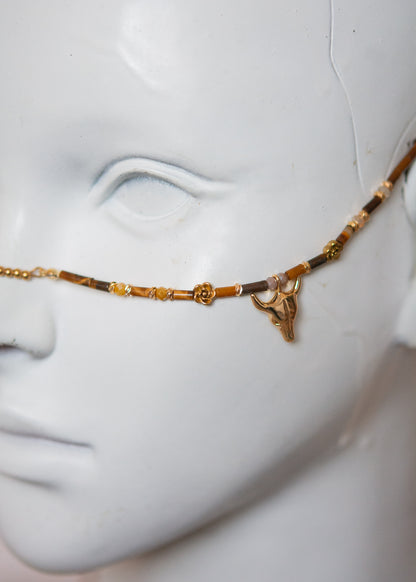 Bijou facial chamanique avec pierre œil de tigre, têtes de taureau et cornes dorées. Accessoire festival, tribal, costume ou photoshoot.