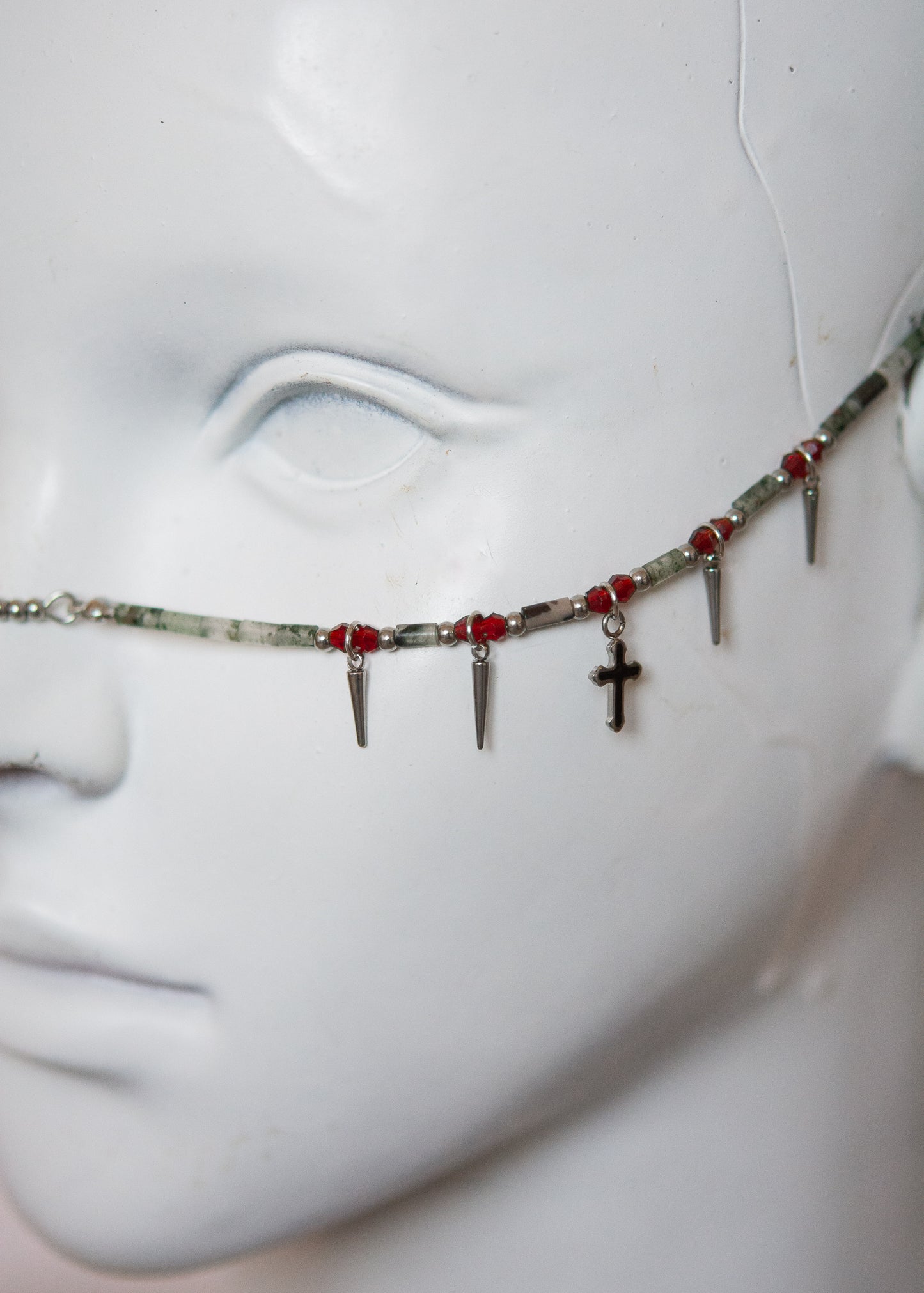 Bijou facial mystique en pierre de sang africaine, croix noires et piques dorées. Parfait pour costume, rituel, shoot gothique ou look ésotérique.