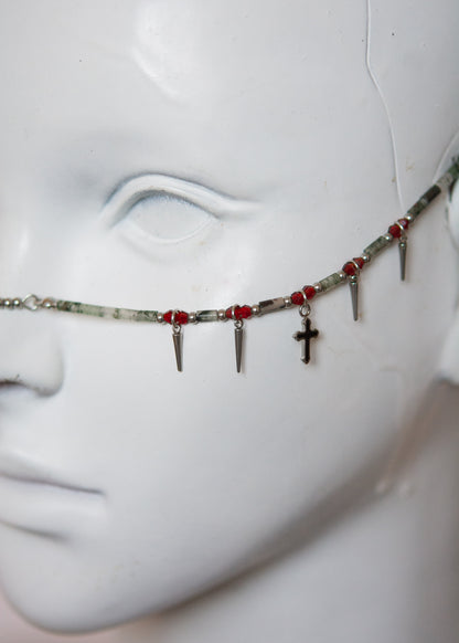 Bijou facial mystique en pierre de sang africaine, croix noires et piques dorées. Parfait pour costume, rituel, shoot gothique ou look ésotérique.