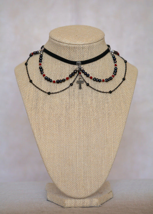 Choker en suède noir avec perles d'eau douce teintées en noir nacré, cristaux rouges et croix. Bijou vampirique goth élégant, inspiré d’une trinité obscure.