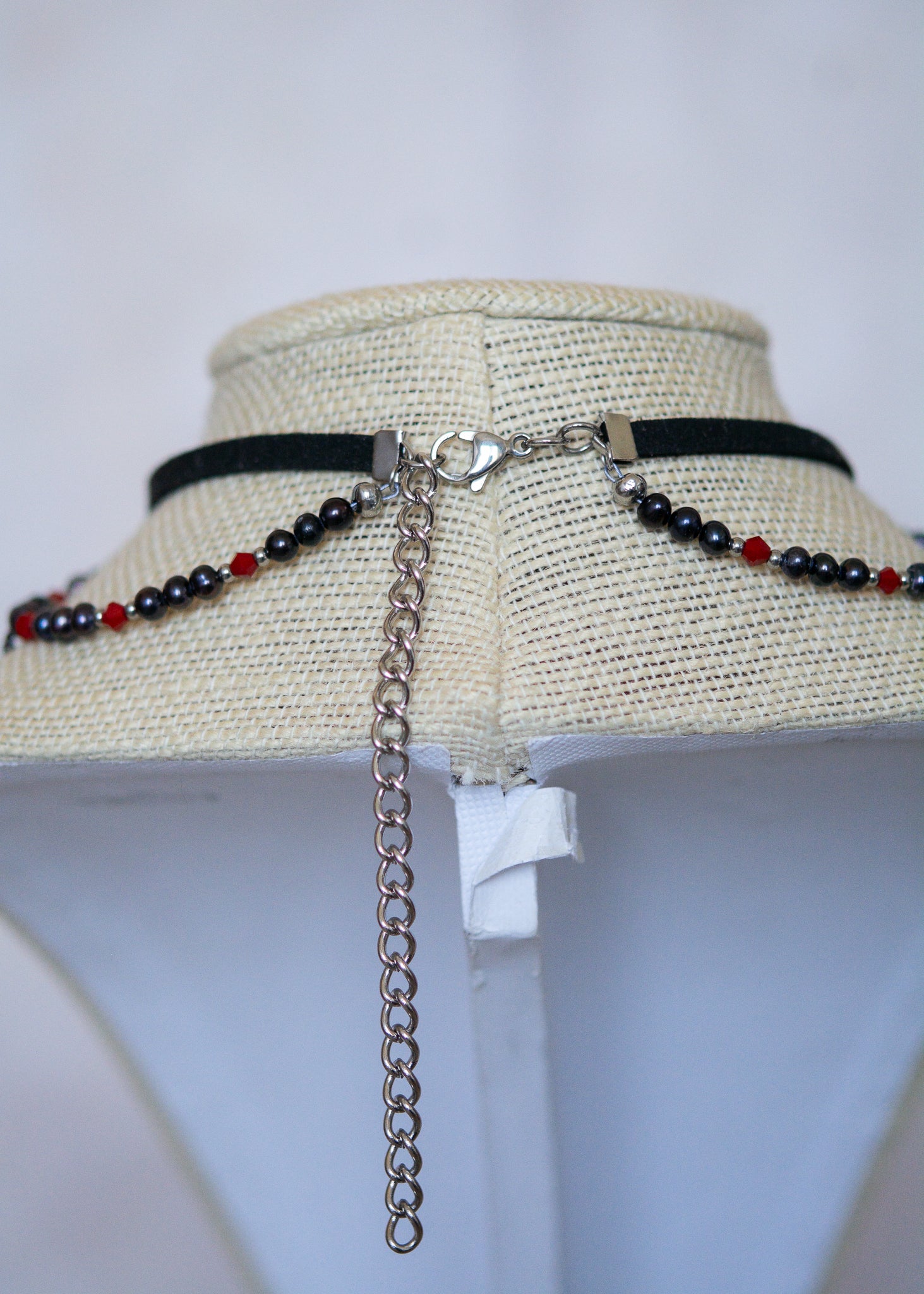 Choker en suède noir avec perles d'eau douce teintées en noir nacré, cristaux rouges et croix. Bijou vampirique goth élégant, inspiré d’une trinité obscure.