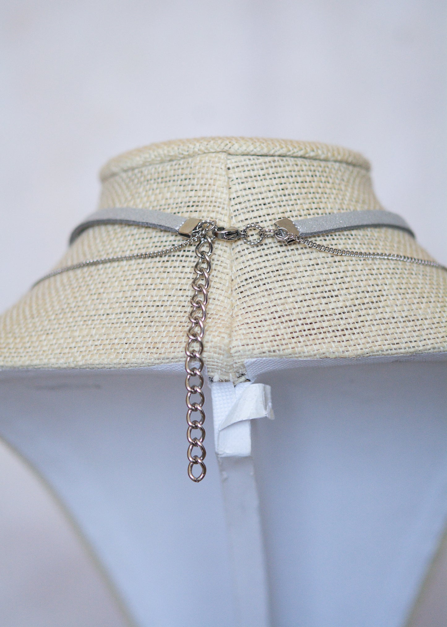 Collier en suède argenté avec soleil émaillé blanc, strass et détails en acier. Bijou léger d’inspiration céleste et angélique.