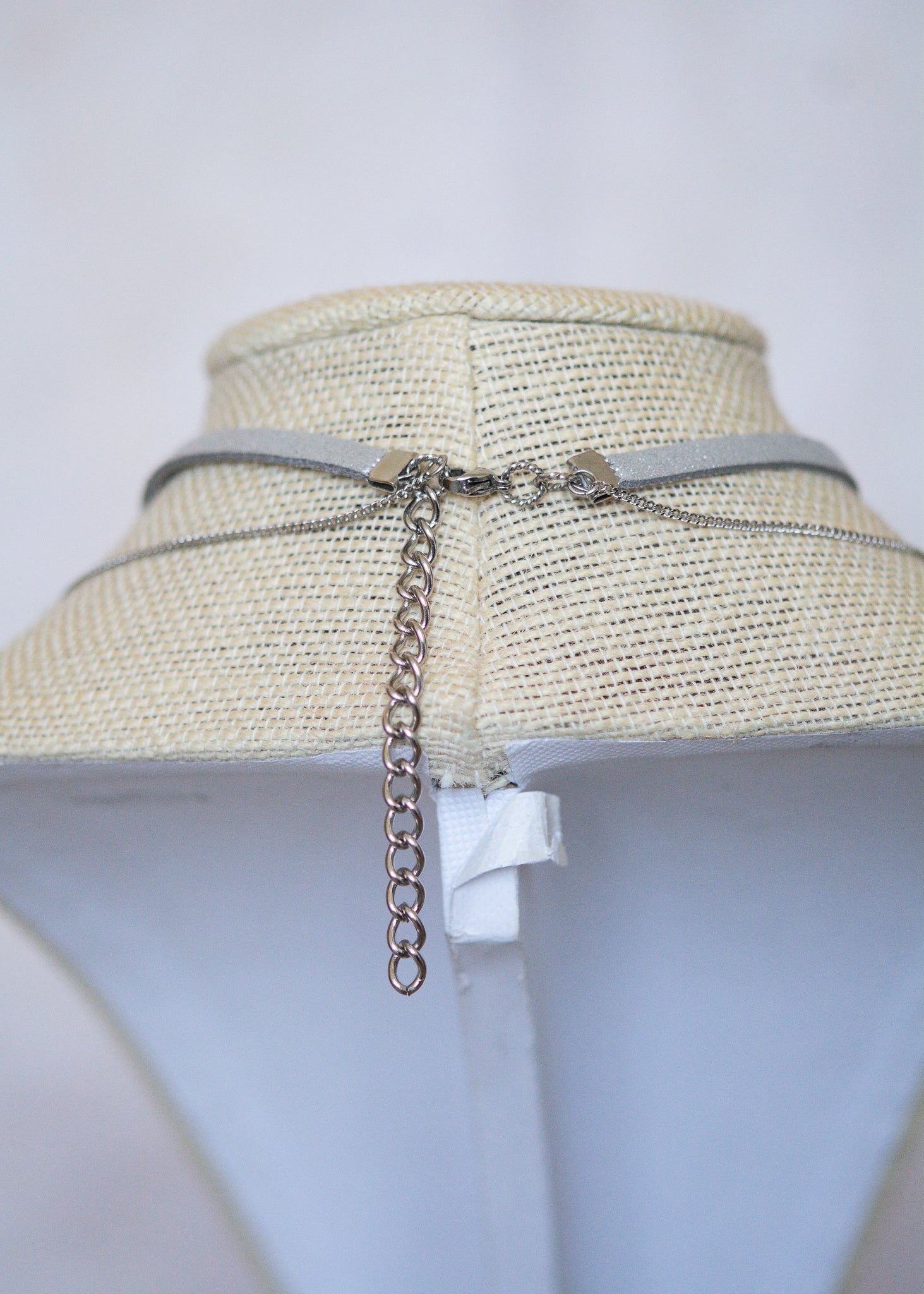 Collier en suède argenté avec soleil émaillé blanc, strass et détails en acier. Bijou léger d’inspiration céleste et angélique.