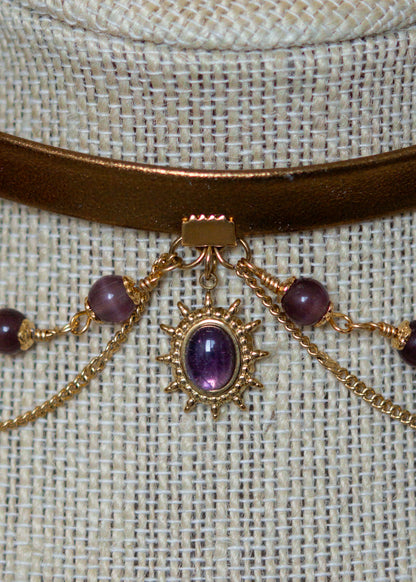 Tour de cou en cuir doré avec soleil mystique, améthyste et perles œil de chat. Bijou oraculaire d’inspiration antique et ésotérique.