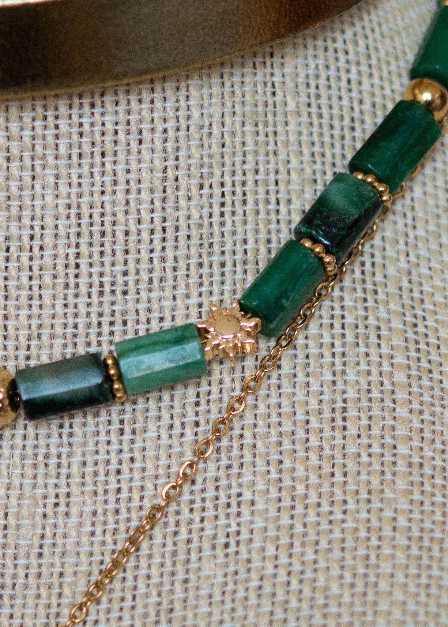 Ras de cou mystique avec cuir doré, émeraude brute, aventurine et breloque soleil. Look witchy boho, parfait pour festival ou tenue rituelle.