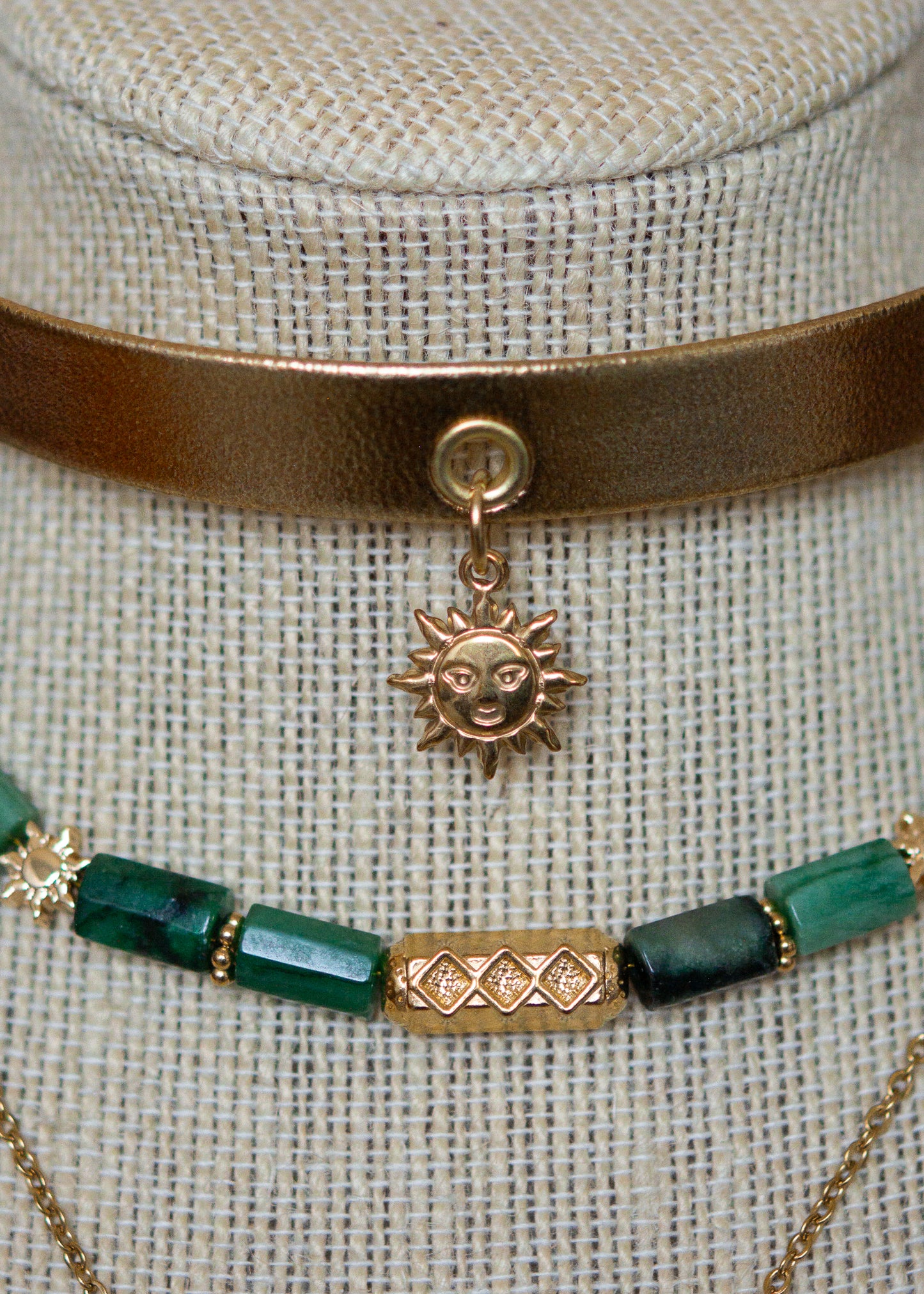 Ras de cou mystique avec cuir doré, émeraude brute, aventurine et breloque soleil. Look witchy boho, parfait pour festival ou tenue rituelle.