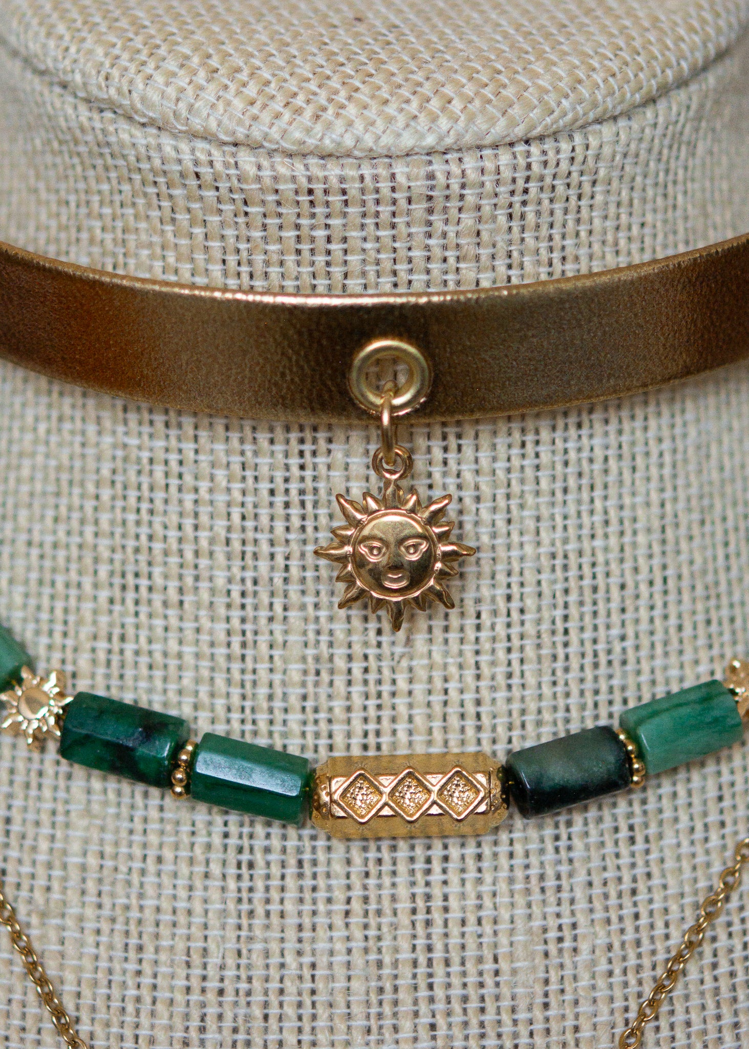 Ras de cou mystique avec cuir doré, émeraude brute, aventurine et breloque soleil. Look witchy boho, parfait pour festival ou tenue rituelle.