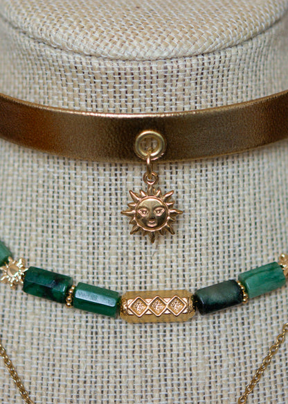 Ras de cou mystique avec cuir doré, émeraude brute, aventurine et breloque soleil. Look witchy boho, parfait pour festival ou tenue rituelle.
