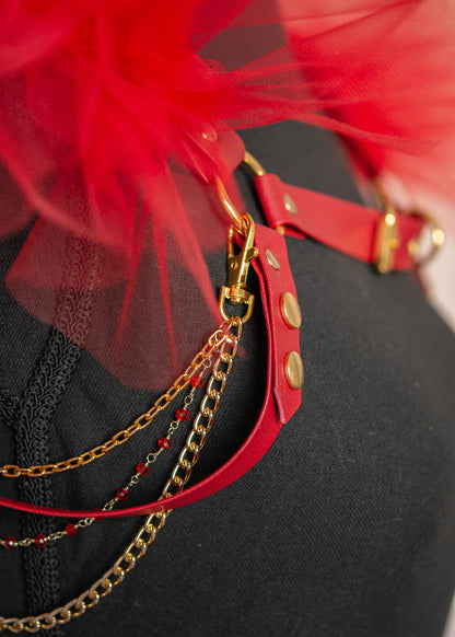 Harnais d'épaules audacieux en vinyle rouge végane avec épaulettes aériennes en tulle rouge et chaînes dorées amovibles. Cette pièce statement transforme instantanément votre silhouette en une célébration de force et de mystère, parfaite pour les festivals, soirées ou pour réinventer vos tenues quotidiennes avec une touche de magie guerrière.
