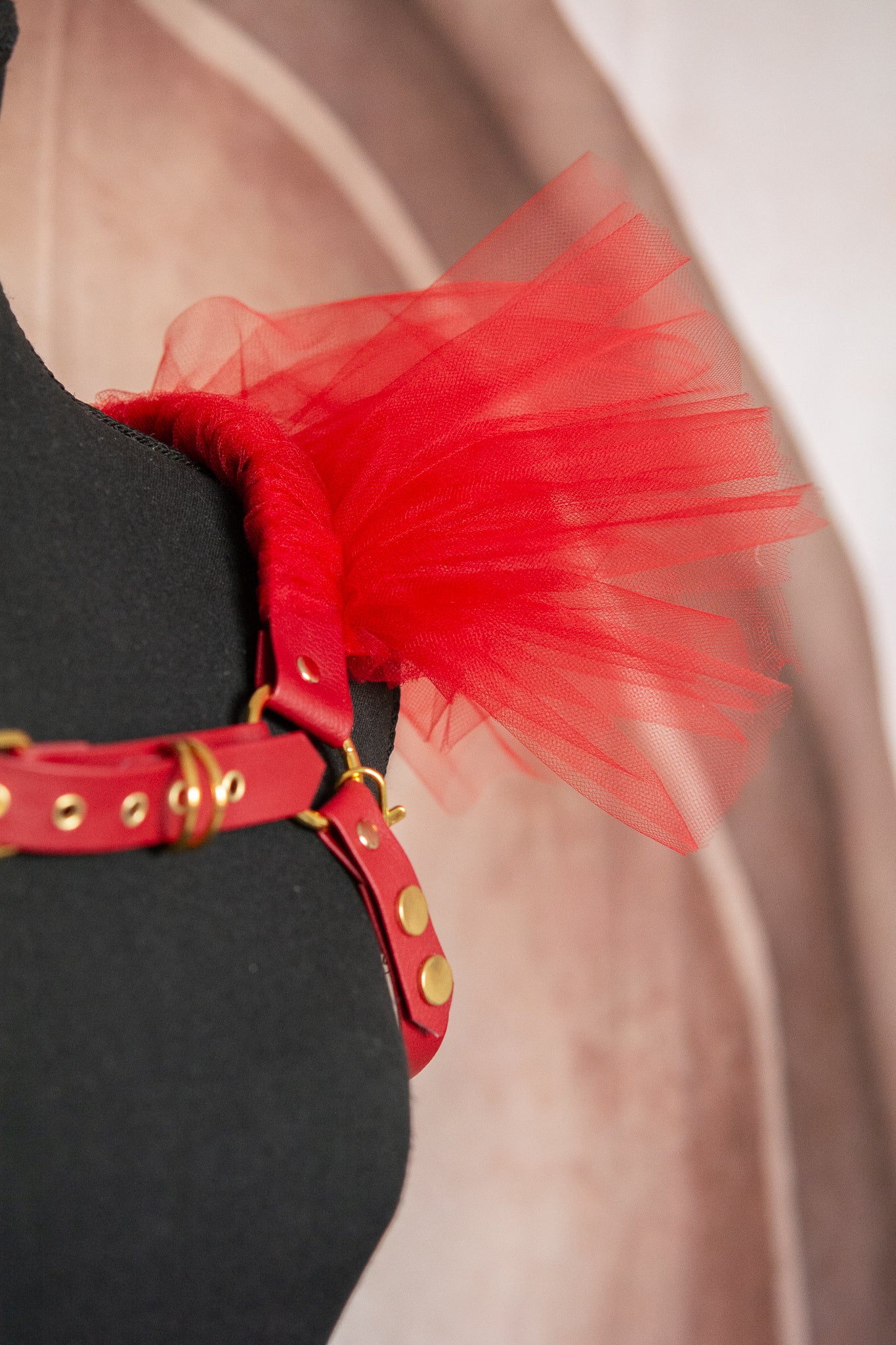 Harnais d'épaules audacieux en vinyle rouge végane avec épaulettes aériennes en tulle rouge et chaînes dorées amovibles. Cette pièce statement transforme instantanément votre silhouette en une célébration de force et de mystère, parfaite pour les festivals, soirées ou pour réinventer vos tenues quotidiennes avec une touche de magie guerrière.