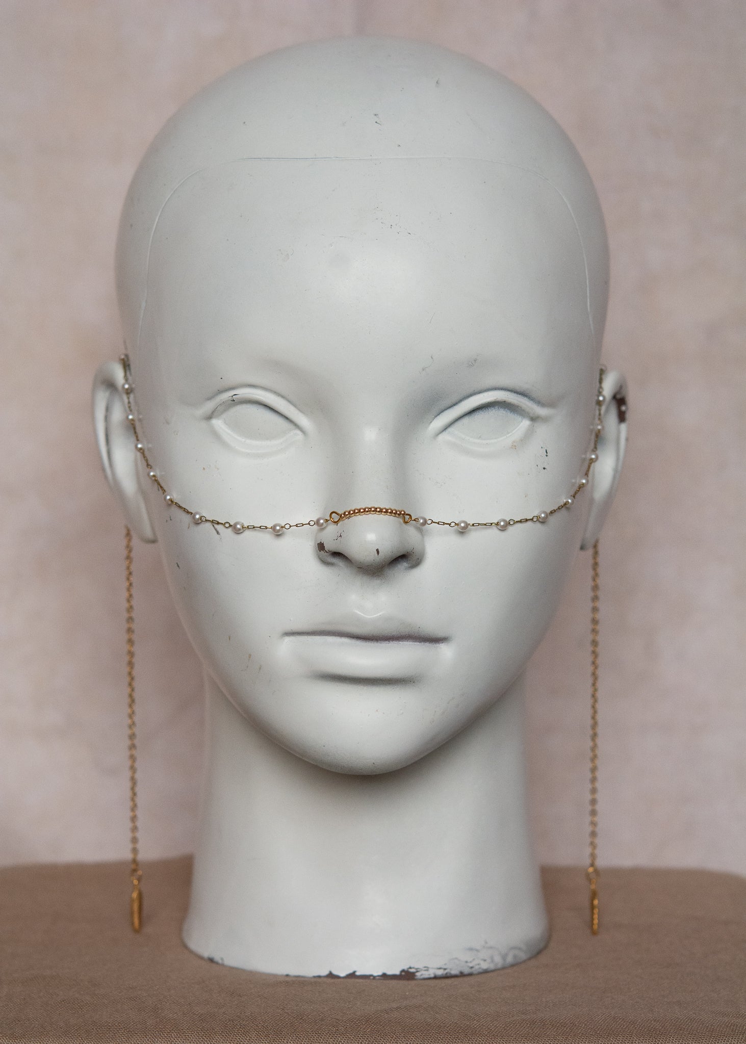 Bijou facial en chaîne d'acier inoxydable plaqué or avec perles synthétiques et plumes dorées. Accessoire léger et aérien, style boho, look festival.