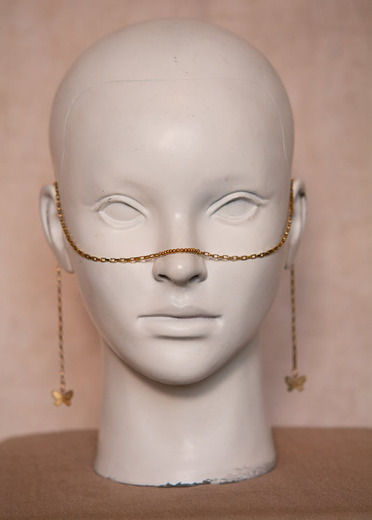 Chaîne de visage dorée, avec maillons géométriques et papillons. Bijou aérien et symbolique inspiré de la mythologie grecque.