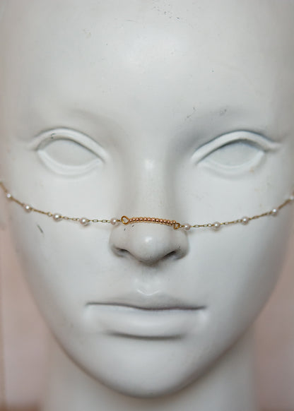 Bijou facial en chaîne d'acier inoxydable plaqué or avec perles synthétiques et plumes dorées. Accessoire léger et aérien, style boho, look festival.