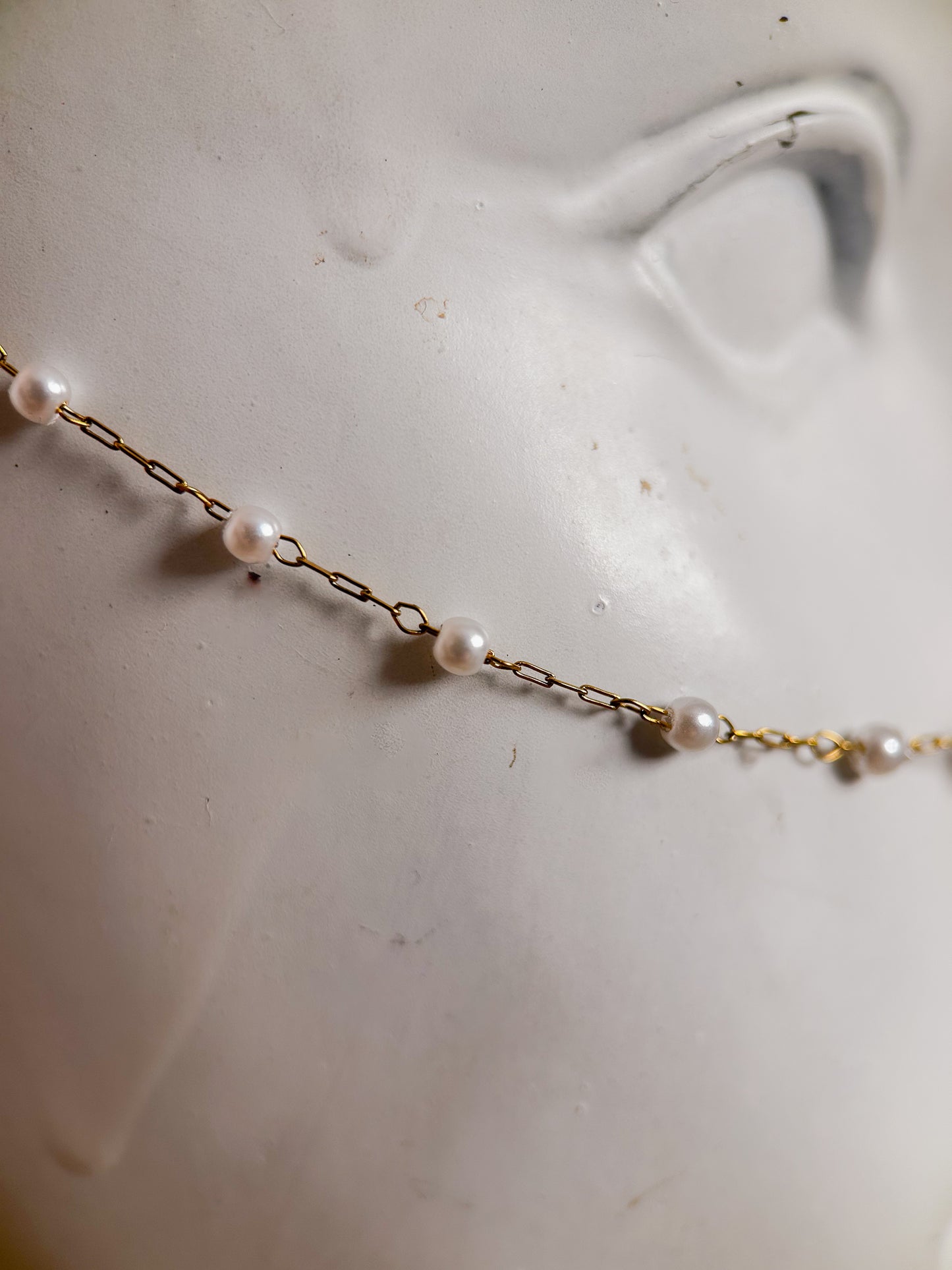 Bijou facial en chaîne d'acier inoxydable plaqué or avec perles synthétiques et plumes dorées. Accessoire léger et aérien, style boho, look festival.