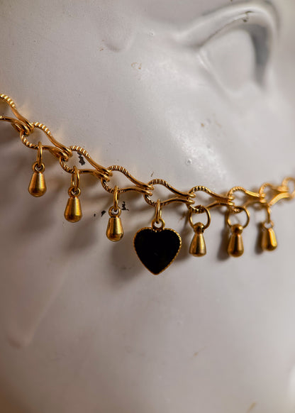 Bijou facial en chaîne d'acier inoxydable plaqué or avec breloques dorées et perles d’agate noire rayée. Accessoire symbolique, contrasté et mystique.