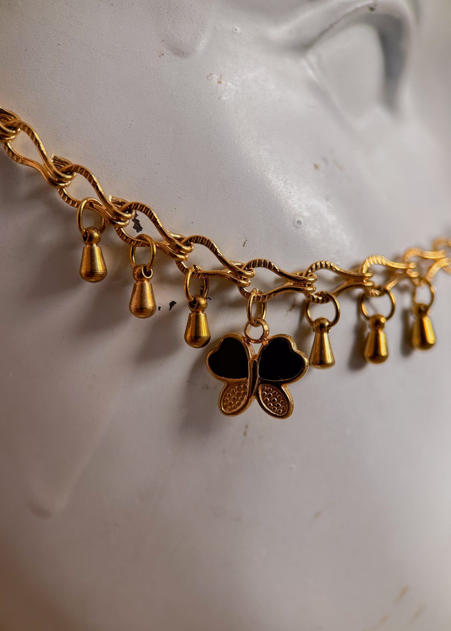 Bijou facial en chaîne d'acier inoxydable plaqué or avec breloques dorées et perles d’agate noire rayée. Accessoire symbolique, contrasté et mystique.