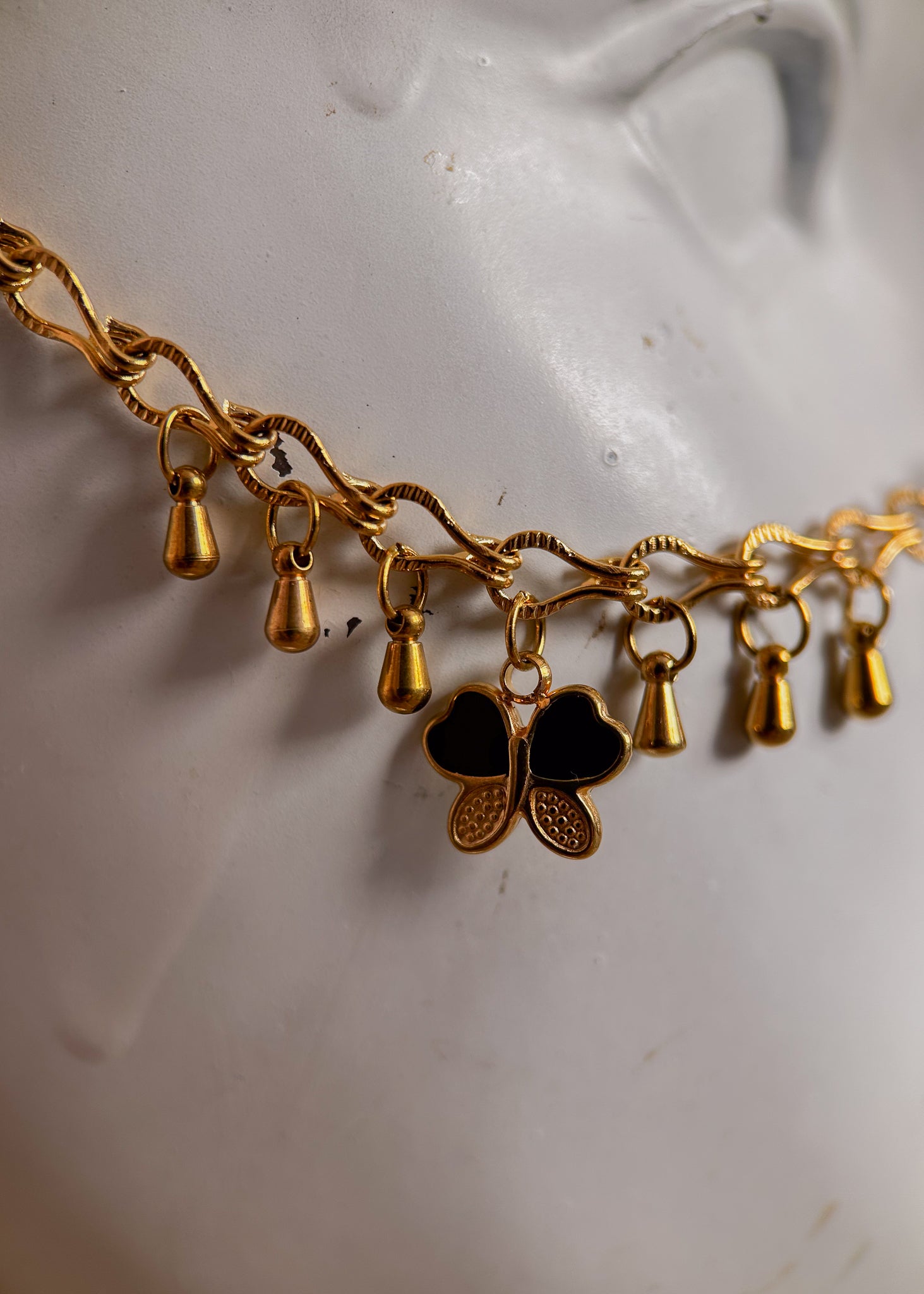 Bijou facial en chaîne d'acier inoxydable plaqué or avec breloques dorées et perles d’agate noire rayée. Accessoire symbolique, contrasté et mystique.