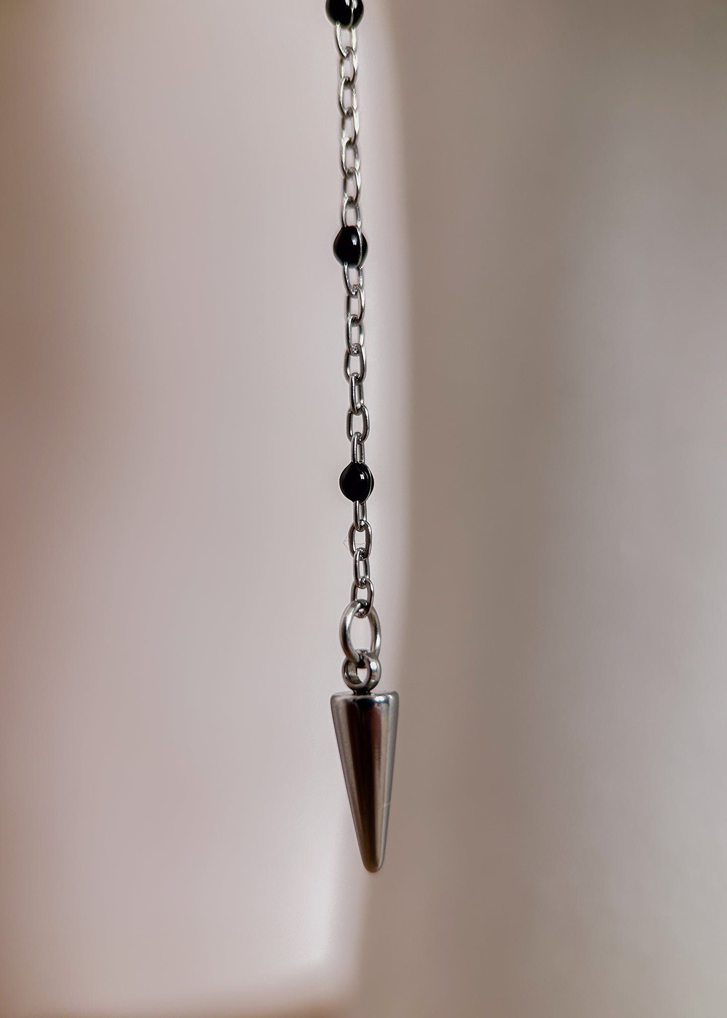 Bijou facial en chaîne fine avec perles d’émail noir et piques. Accessoire sombre et délicat pour look alternatif minimaliste.