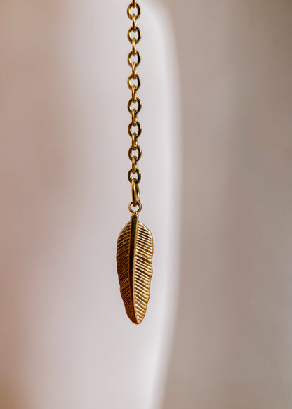 Bijou facial en chaîne d'acier inoxydable plaqué or avec perles synthétiques et plumes dorées. Accessoire léger et aérien, style boho, look festival.