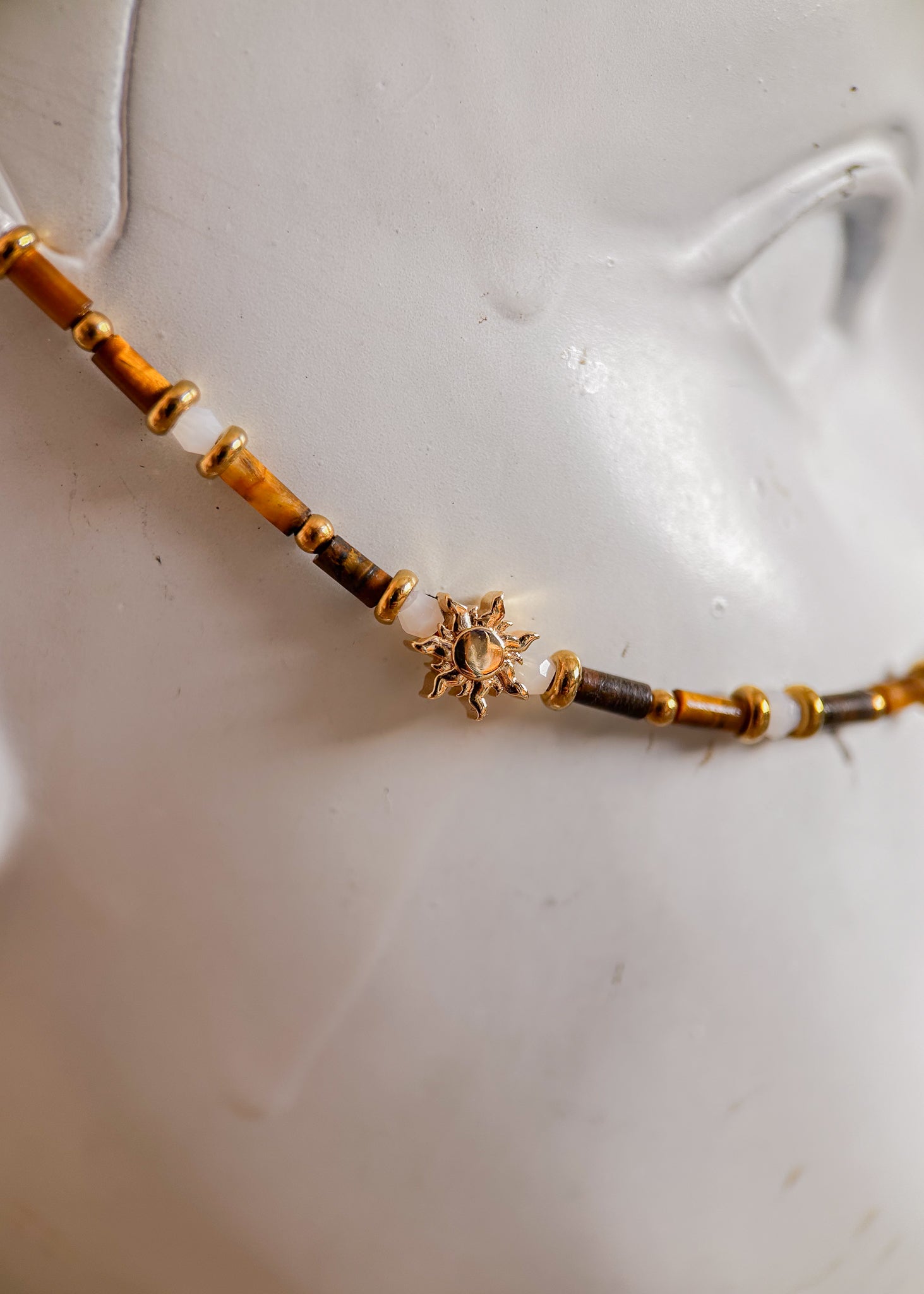 Bijou facial acier inoxydable doré, œil de tigre et howlite blanche avec détails soleil. Accessoire solaire et mystique, parfait pour festival ou événement.