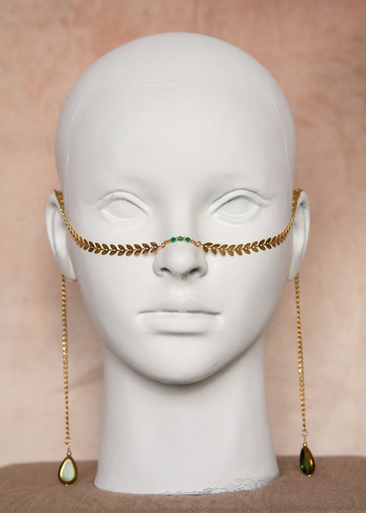 Chaîne de visage en acier inoxydable plaqué or motif feuilles géométriques et cristaux vert émeraude. Bijou facial bohème, look forêt mystique et royal.