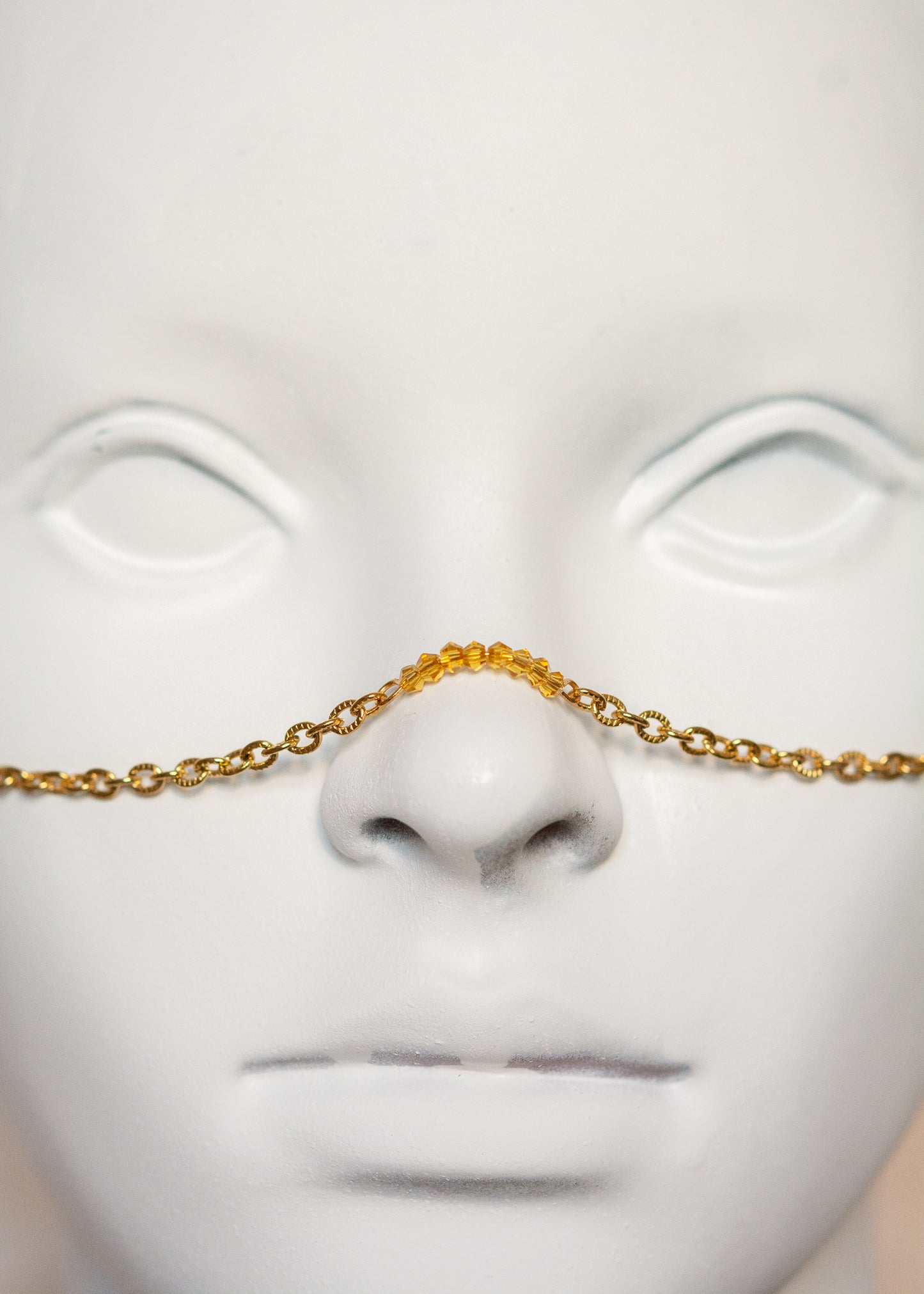 Chaîne de visage en acier inoxydable plaqué or avec cristaux ocre orangé et piques dorées. Bijou facial festival, look solaire chaud et intense.