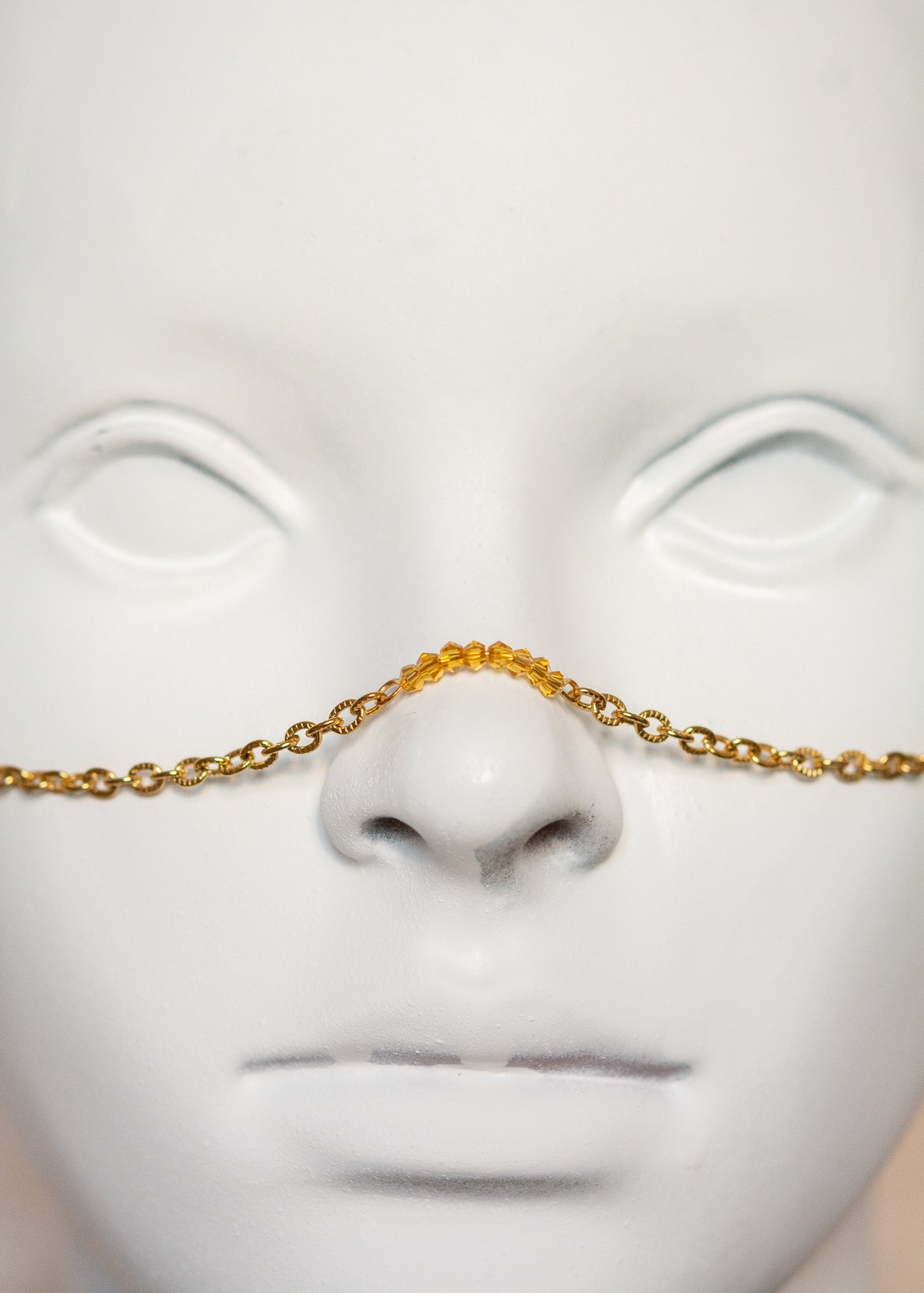 Chaîne de visage en acier inoxydable plaqué or avec cristaux ocre orangé et piques dorées. Bijou facial festival, look solaire chaud et intense.