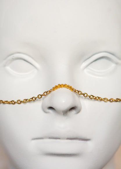 Chaîne de visage en acier inoxydable plaqué or avec cristaux ocre orangé et piques dorées. Bijou facial festival, look solaire chaud et intense.