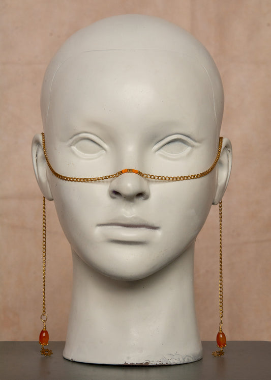 Chaîne de visage dorée inspirée de l’éclat du soleil, ornée de pierres d’agate orange et charms soleil bohème. Bijou facial unisexe en acier inoxydable, parfait pour festivals, tenues audacieuses et événements spéciaux.