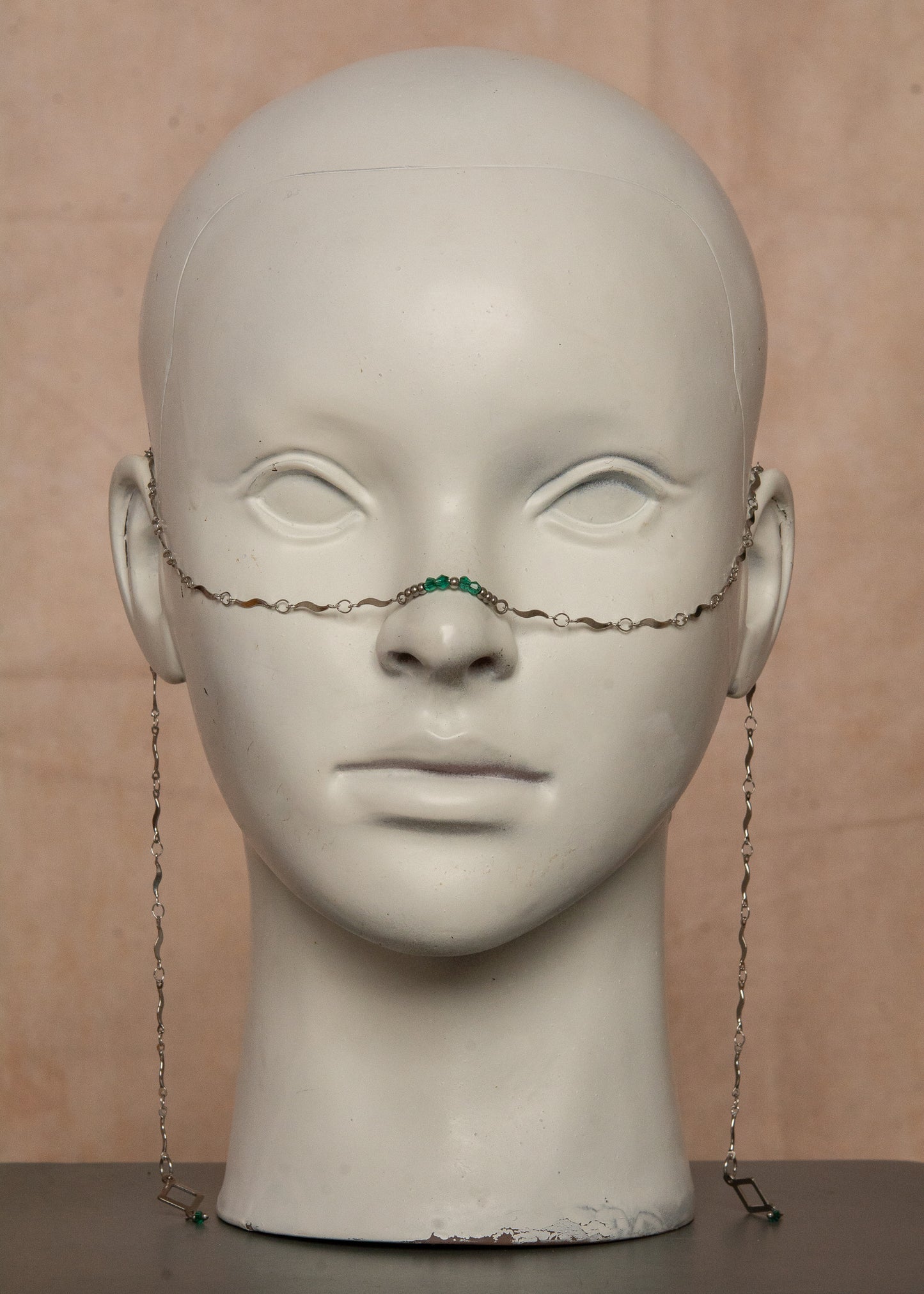 Chaîne de visage argentée en acier inoxydable, inspirée de la mythologie du serpent Basilic. Détails fluides et cristaux vert émeraude pour un look hypnotique et mystérieux, parfait pour les âmes audacieuses.