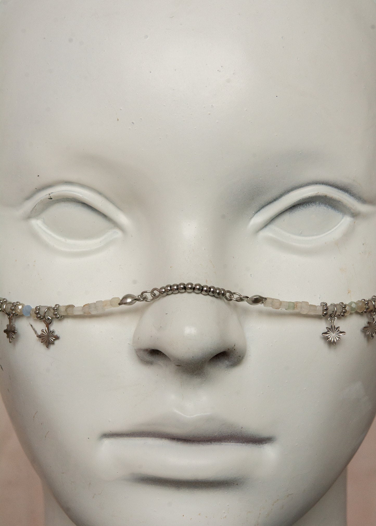 Bijou facial artisanal combinant agate blanche, cristaux bleus et acier inoxydable. Accessoire céleste avec charmes étoiles et pierres de lune noires aux reflets holographiques transformées en lanternes orientales. Pièce unique apportant sérénité et équilibre, parfaite pour festivals nocturnes et événements mystiques.