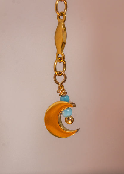 Chaîne de visage unisexe en acier inoxydable doré, design fluide avec croissants de lune et perles de rocaille bleue. Bijou minimaliste et mystique, parfait pour festivals, événements et looks inspirés de l'éclipse solaire et lunaire.