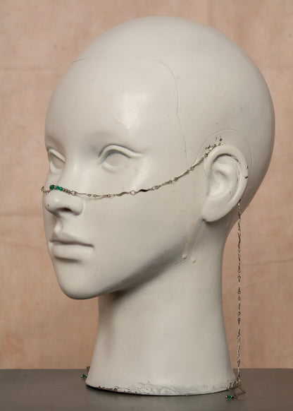 Chaîne de visage argentée en acier inoxydable, inspirée de la mythologie du serpent Basilic. Détails fluides et cristaux vert émeraude pour un look hypnotique et mystérieux, parfait pour les âmes audacieuses.